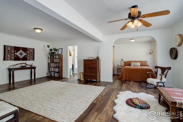 bedroom featuring a ceiling fan, wood finished floors, arched walkways, a textured ceiling, and crown molding