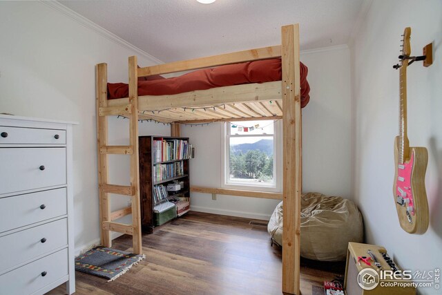 bedroom with crown molding, baseboards, and wood finished floors