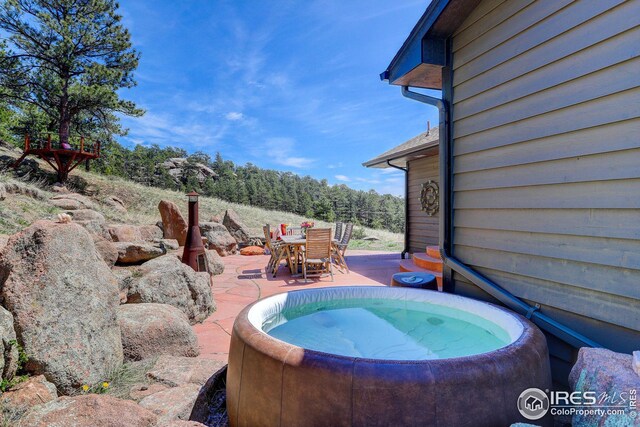 view of swimming pool with outdoor dining area, a hot tub, and a patio area