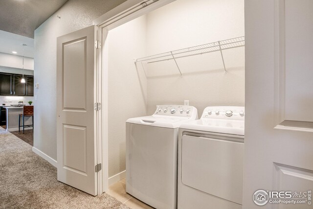 laundry room featuring light carpet, separate washer and dryer, and a textured ceiling