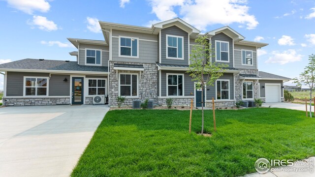 view of front of property featuring a garage, a front lawn, and central air condition unit