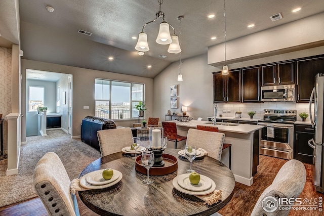 dining area featuring a textured ceiling, lofted ceiling, dark wood-type flooring, and sink