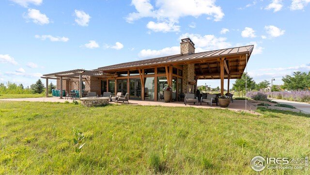 back of property with ceiling fan, a pergola, an outdoor fire pit, a lawn, and a patio area