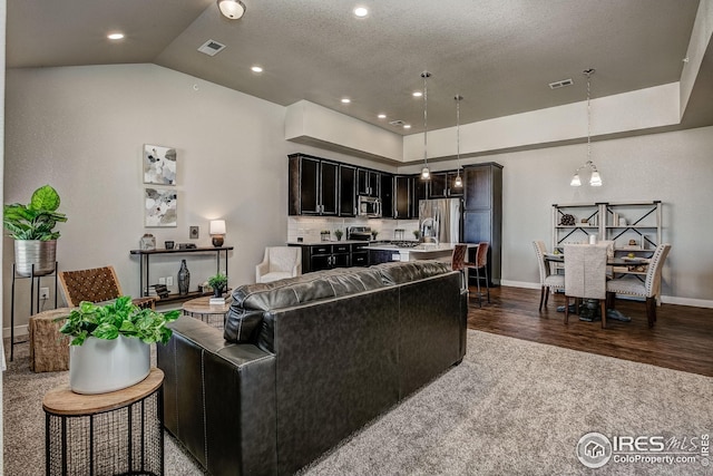 living room with a textured ceiling, vaulted ceiling, and dark hardwood / wood-style flooring