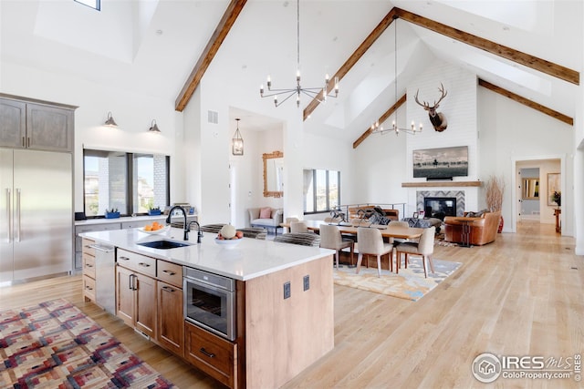 kitchen with high vaulted ceiling, sink, a center island with sink, and built in appliances