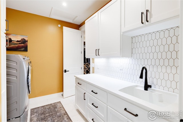 laundry area featuring sink, washing machine and clothes dryer, cabinets, and light tile patterned flooring