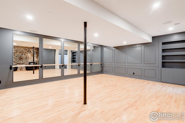 basement with built in features and light hardwood / wood-style flooring