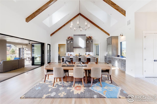dining room with beamed ceiling, an inviting chandelier, light wood-type flooring, and high vaulted ceiling