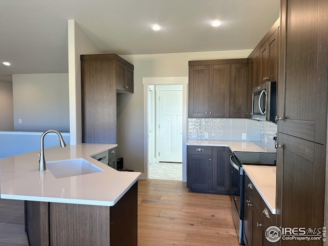 kitchen featuring sink, tasteful backsplash, light hardwood / wood-style flooring, electric stove, and dark brown cabinets