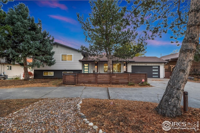 tri-level home featuring a fenced front yard, concrete driveway, and an attached garage