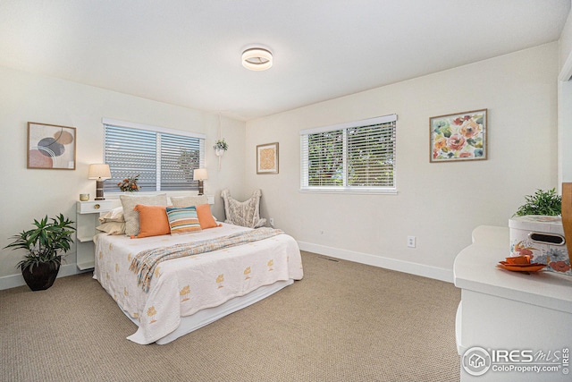 bedroom featuring multiple windows, carpet, visible vents, and baseboards