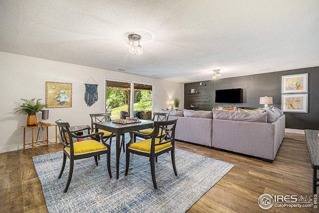 dining space featuring dark wood-type flooring, a textured ceiling, and baseboards