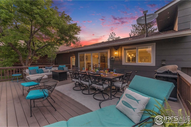 deck at dusk with outdoor dining space, a grill, and an outdoor living space