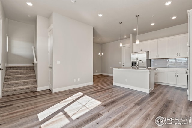 kitchen featuring decorative light fixtures, dark brown cabinetry, appliances with stainless steel finishes, and an island with sink