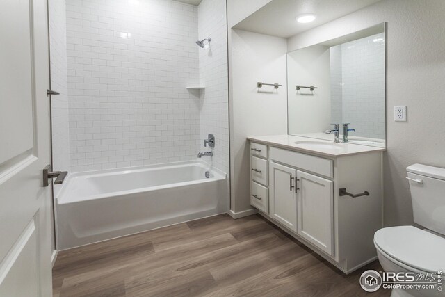 full bathroom with vanity, tiled shower / bath combo, wood-type flooring, and toilet