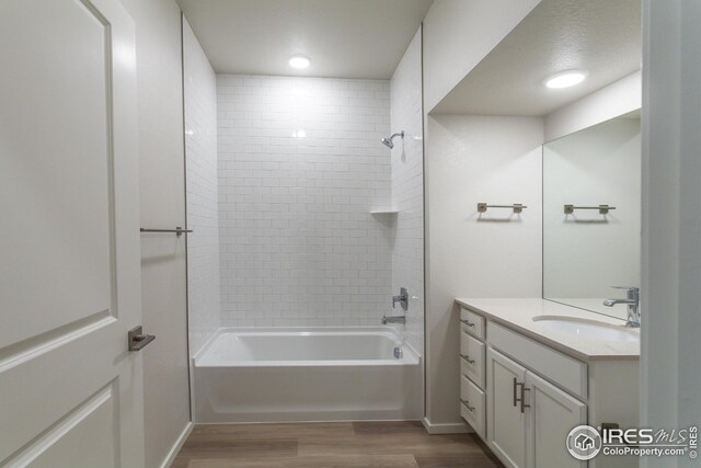 bathroom with vanity, hardwood / wood-style floors, tiled shower / bath combo, and a textured ceiling