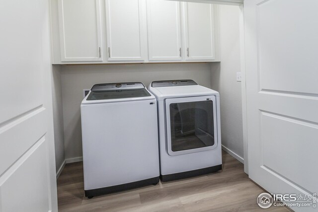 clothes washing area featuring light hardwood / wood-style flooring, separate washer and dryer, and cabinets