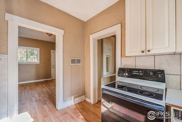 kitchen with white cabinetry, white range with electric stovetop, and light hardwood / wood-style flooring