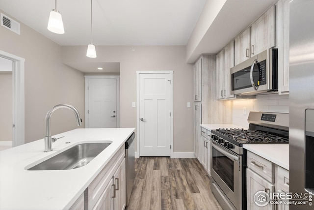 kitchen featuring sink, light wood-type flooring, decorative light fixtures, stainless steel appliances, and decorative backsplash