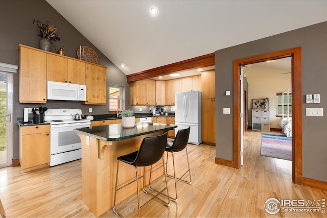 kitchen featuring lofted ceiling, light hardwood / wood-style flooring, white appliances, a center island, and a healthy amount of sunlight