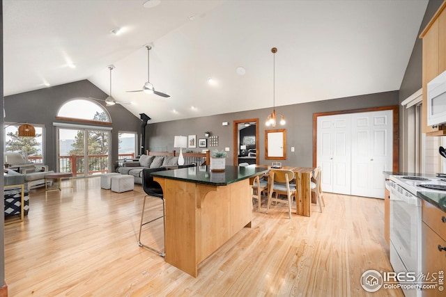 kitchen featuring decorative light fixtures, ceiling fan with notable chandelier, white appliances, a center island, and light hardwood / wood-style flooring