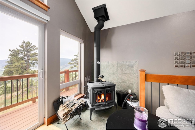 bedroom featuring a mountain view, a wood stove, lofted ceiling, and tile patterned flooring