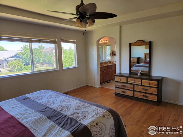 bedroom featuring light hardwood / wood-style flooring, ensuite bath, and ceiling fan