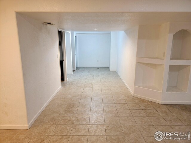 hall with light tile patterned floors and a textured ceiling