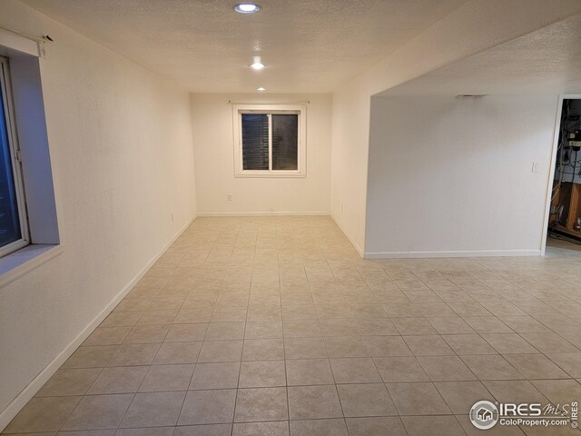 tiled empty room featuring a textured ceiling