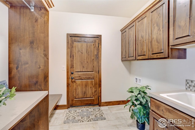 washroom featuring washer hookup, light tile patterned flooring, cabinets, and sink