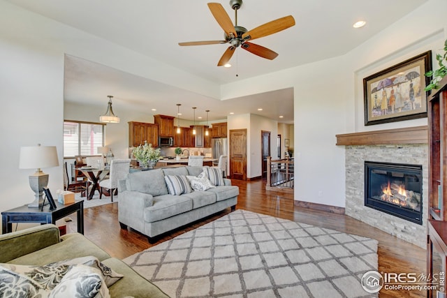 living room with ceiling fan, dark hardwood / wood-style floors, and a fireplace