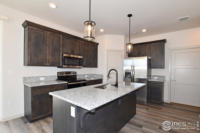 kitchen with hanging light fixtures, sink, stainless steel appliances, and dark brown cabinets