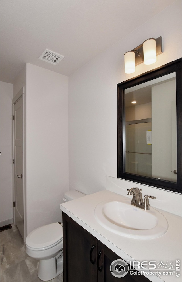 bathroom featuring vanity, toilet, and a shower with shower door