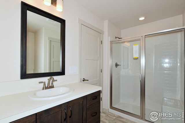 bathroom featuring a shower with door and vanity