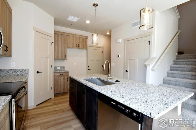 kitchen with appliances with stainless steel finishes, hanging light fixtures, a kitchen island with sink, and sink