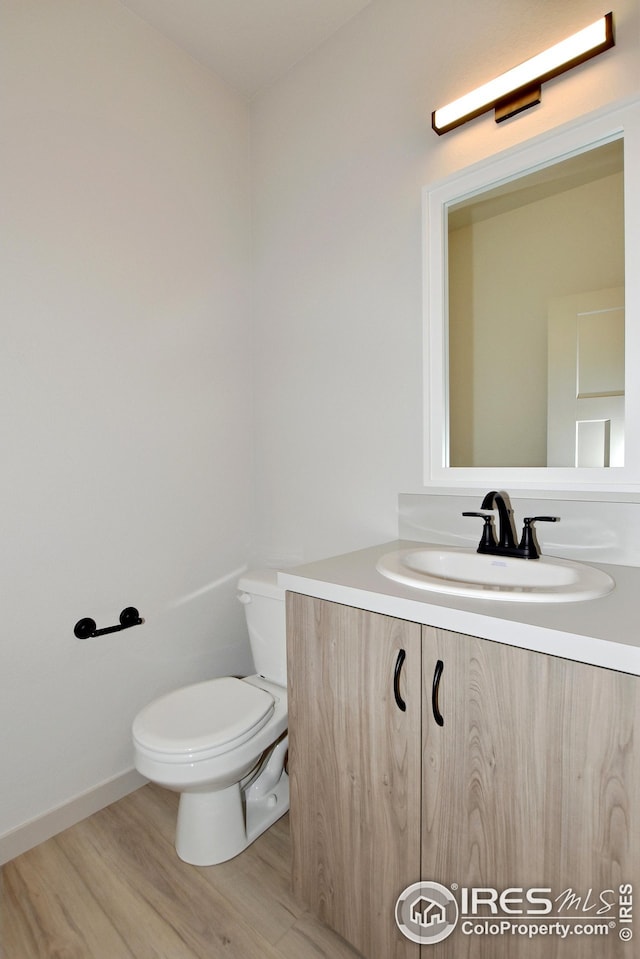 bathroom with hardwood / wood-style floors, vanity, and toilet