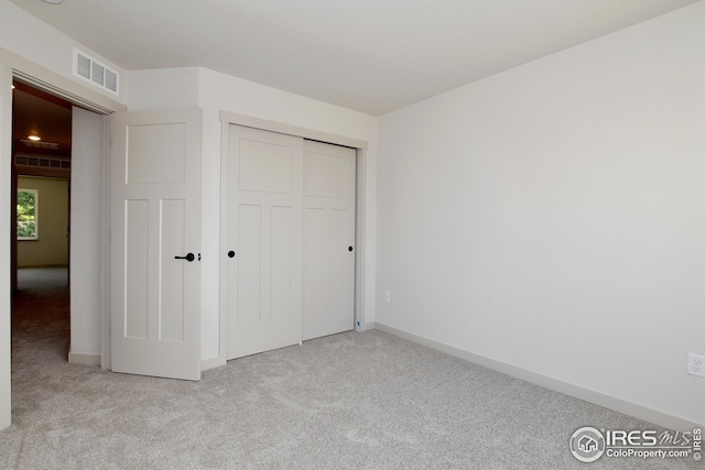 unfurnished bedroom with a closet and light carpet