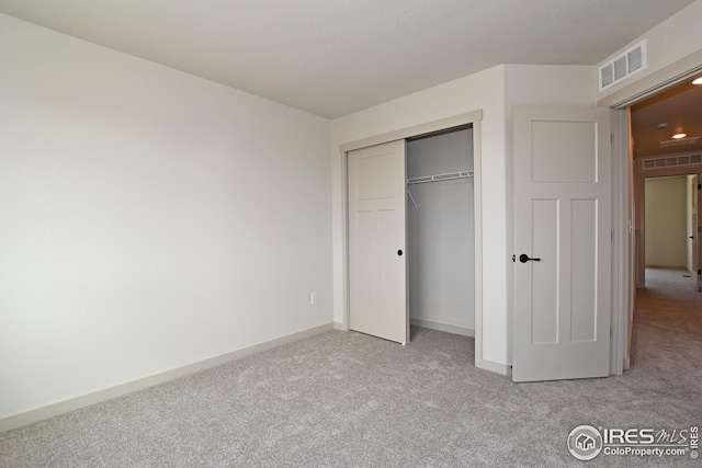 unfurnished bedroom with light colored carpet and a closet