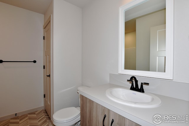 bathroom featuring parquet floors, vanity, and toilet