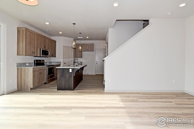 kitchen featuring sink, decorative light fixtures, a center island with sink, a breakfast bar, and appliances with stainless steel finishes