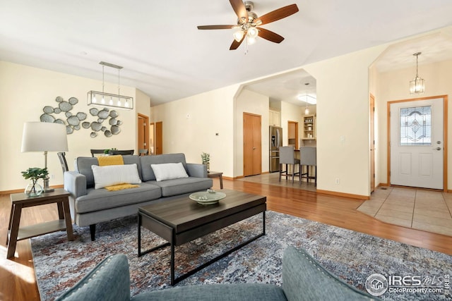 living room with ceiling fan with notable chandelier and wood-type flooring