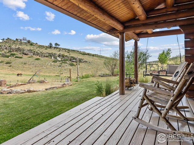 wooden deck with a rural view and a lawn