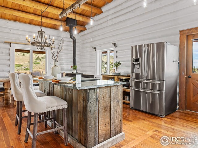 kitchen featuring log walls, wooden ceiling, stainless steel fridge with ice dispenser, and light wood-type flooring