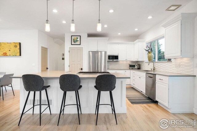2870 18th St, Boulder, CO 80304 - kitchen with appliances with stainless steel finishes, light hardwood / wood-style flooring, a center island, and decorative backsplash