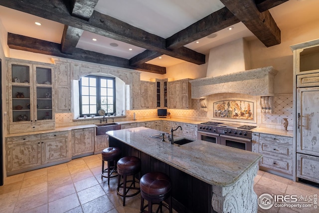 kitchen with sink, double oven range, backsplash, range hood, and a large island