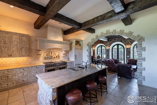 kitchen featuring extractor fan, tasteful backsplash, a kitchen breakfast bar, range with two ovens, and a spacious island