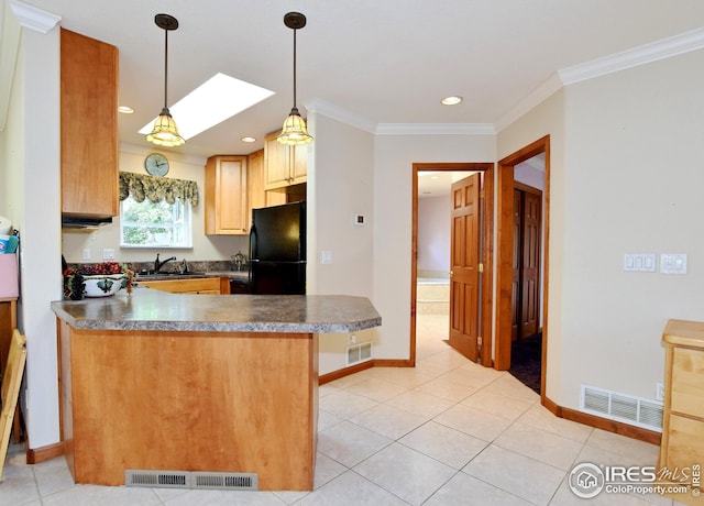 kitchen featuring crown molding, black refrigerator, hanging light fixtures, a skylight, and a kitchen breakfast bar