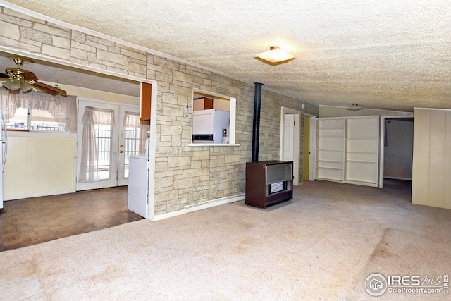 unfurnished living room featuring carpet flooring, a wood stove, a textured ceiling, and french doors