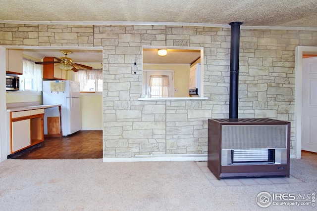 kitchen featuring dark colored carpet, a textured ceiling, a wood stove, white fridge, and ceiling fan