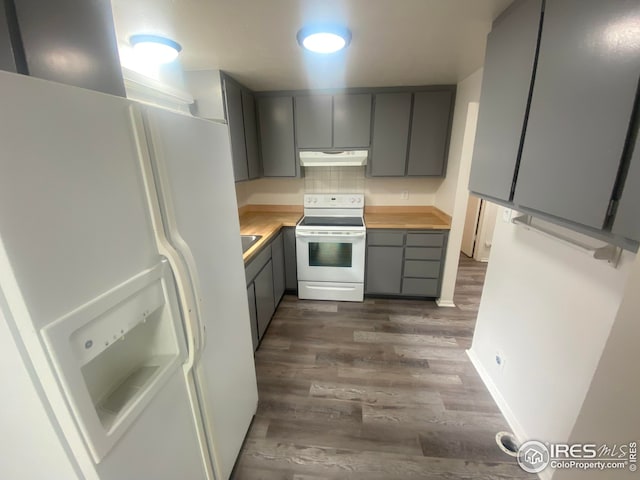 kitchen with dark wood-type flooring, butcher block countertops, gray cabinetry, tasteful backsplash, and white appliances